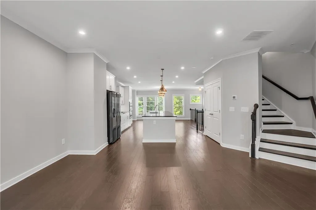 Unfurnished living room with crown molding, recessed lighting, dark wood-style flooring, and stairway