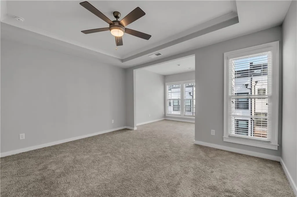 Carpeted spare room with a raised ceiling, a ceiling fan, and a smoke detector