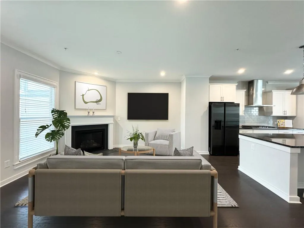 Living area with ornamental molding, recessed lighting, a glass covered fireplace, and dark wood-style flooring