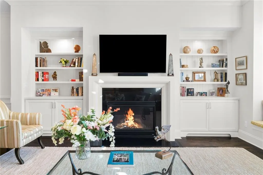 Fireplace with dark stone surround, custom built-in white cabinetry, integrated open shelving, and wood-finish flooring