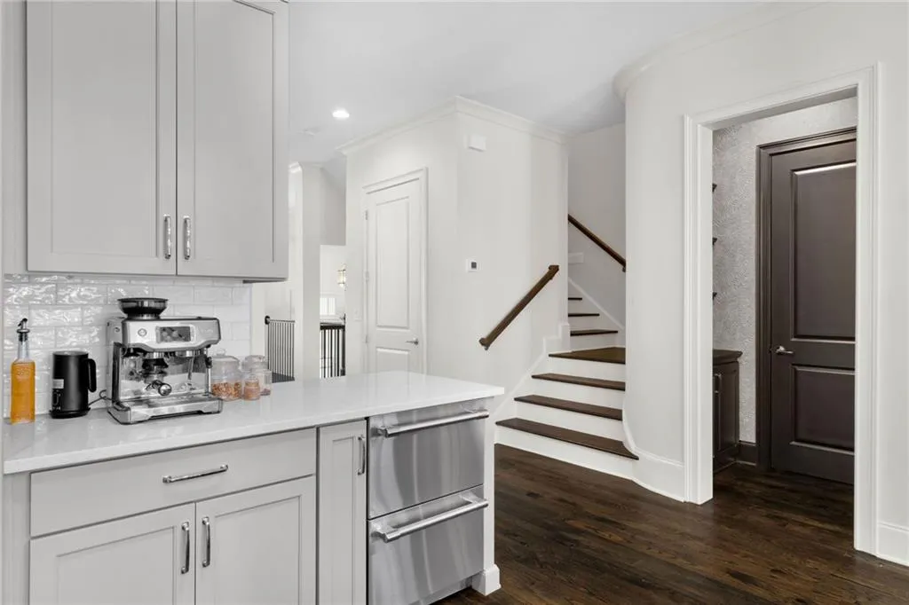 Shaker-style cabinetry, quartz countertops, subway tile backsplash, stainless steel drawer refrigeration, and wood-finish flooring
