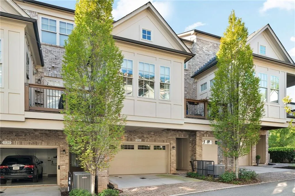 Multi-level exterior featuring a brick and composite siding façade, elevated wooden balcony, multi-pane windows, and attached garage