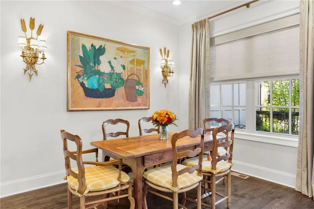 Dining area featuring dark wood-finish flooring, crown molding, multi-pane windows, and dual ornate wall-mounted sconces