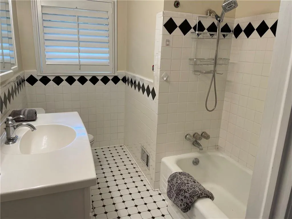 Jazzy full bathroom featuring toilet, vanity, tile patterned floors, tile walls, and tiled shower / bath combo