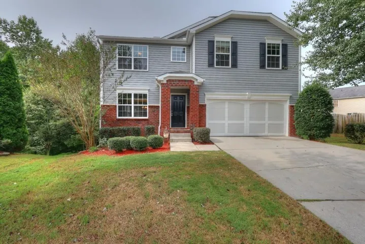 Two-story residence featuring a brick and siding exterior, front entry with transom window, and an attached two-car garage