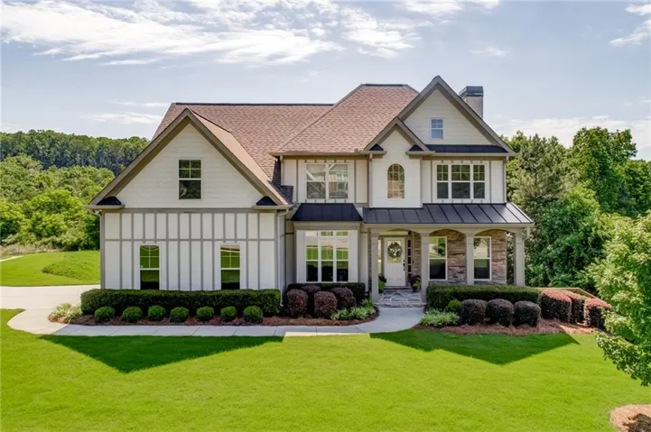 Traditional-style residence featuring a prominent front gable, stone column accents, covered entry, and manicured landscaping