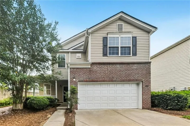 Two-story exterior with a brick and siding facade, an attached front-entry garage, and a concrete driveway