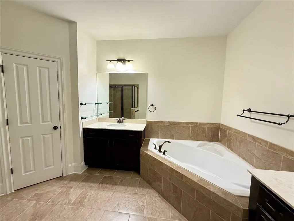 Full bathroom with vanity, a garden tub, a shower stall, and light tile patterned flooring