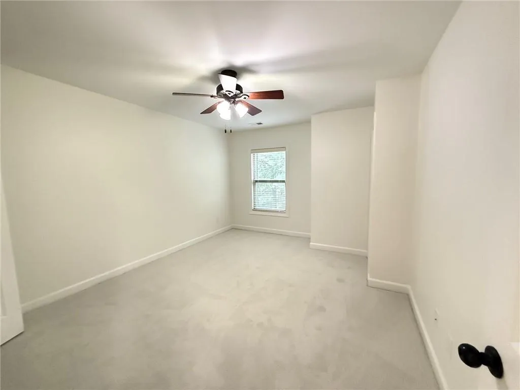 Empty room with light carpet and ceiling fan