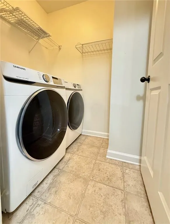 Washroom featuring washing machine and dryer and light tile patterned floors