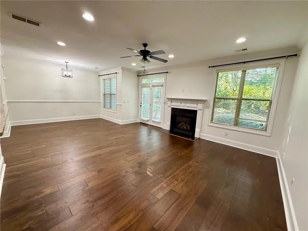 Unfurnished living room with crown molding, recessed lighting, a fireplace, dark wood-style flooring, and ceiling fan