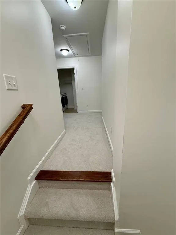 Staircase with carpet, attic access, and washer / dryer