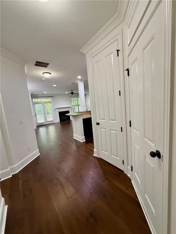 Corridor featuring dark wood-type flooring and ornamental molding