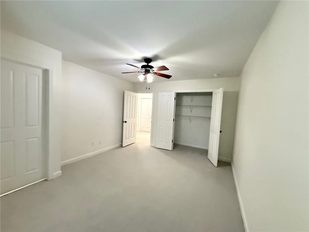 Unfurnished bedroom with ceiling fan and carpet