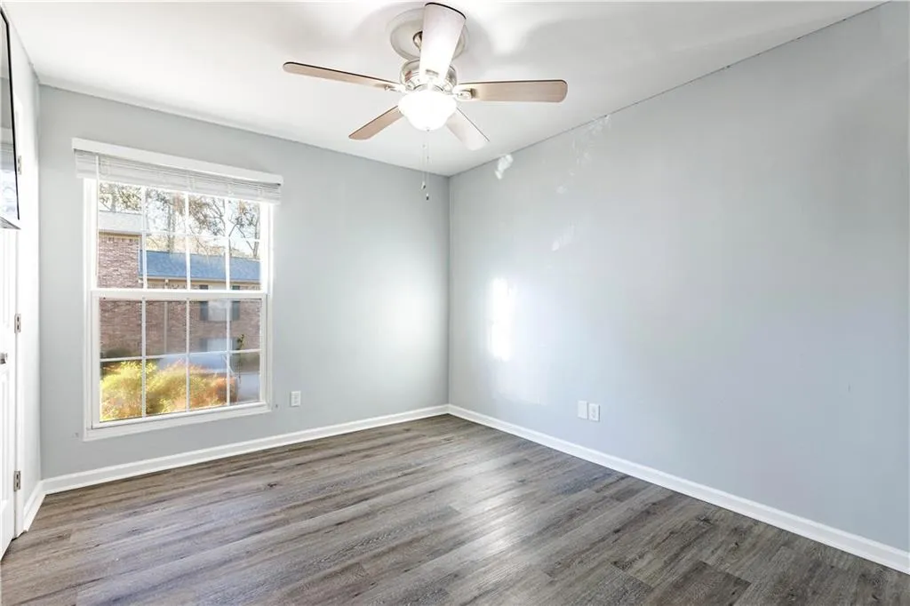 Unfurnished room featuring plenty of natural light, ceiling fan, and dark wood-type flooring