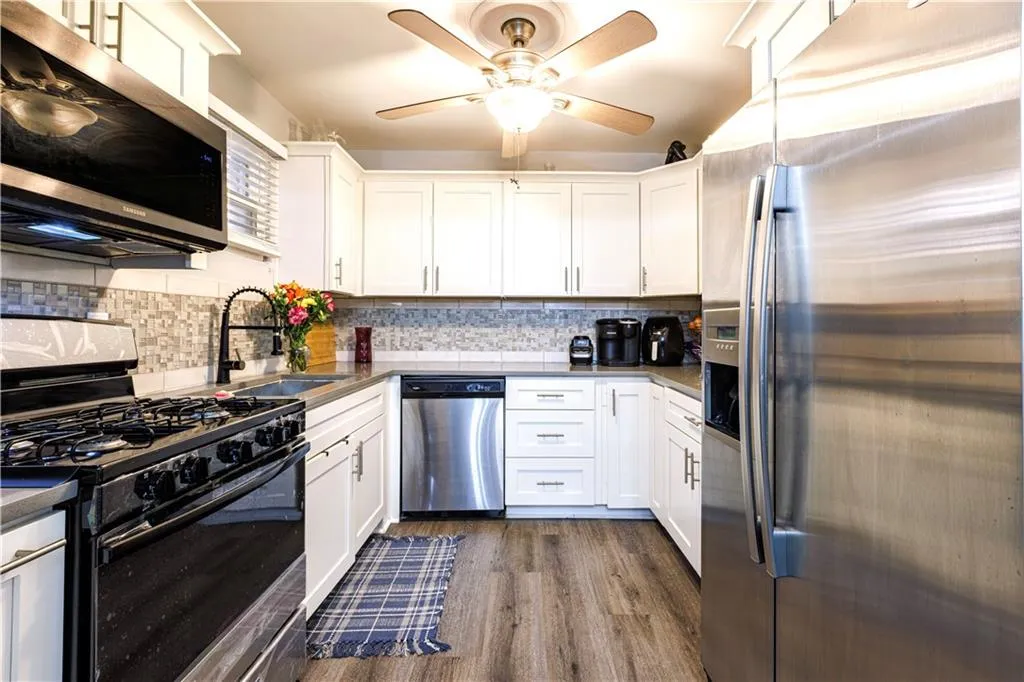 Kitchen featuring white cabinetry, stainless steel appliances, tasteful backsplash, and ceiling fan