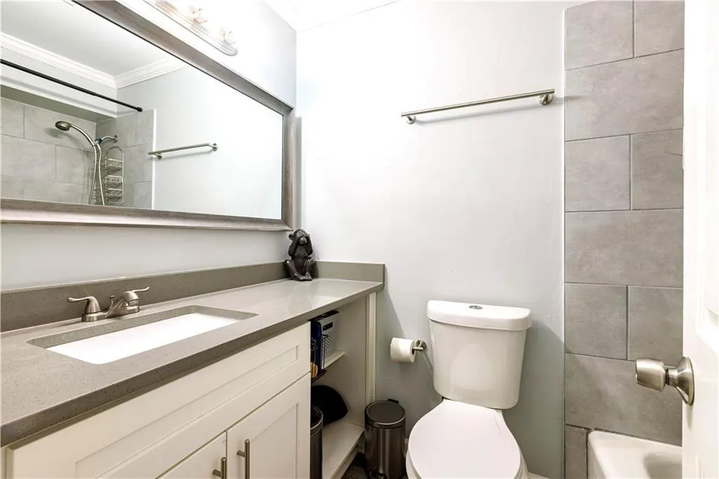 Full bathroom with tiled shower / bath, vanity with extensive cabinet space, crown molding, and toilet