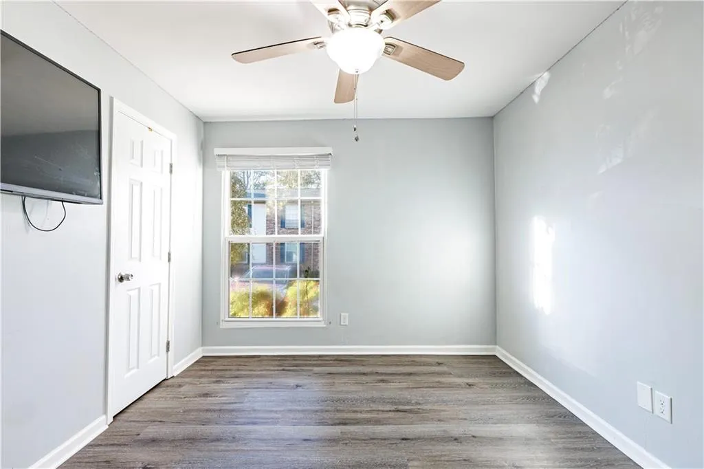 Empty room with dark wood-type flooring and ceiling fan