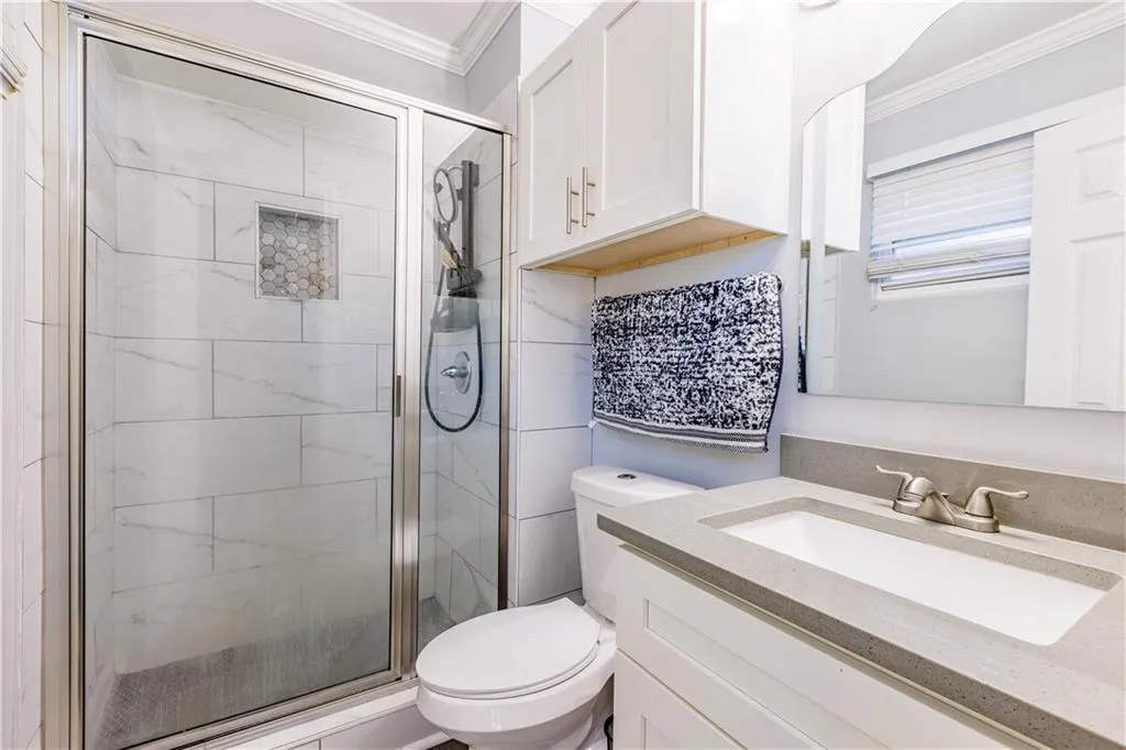 Bathroom with an enclosed shower, crown molding, toilet, and vanity