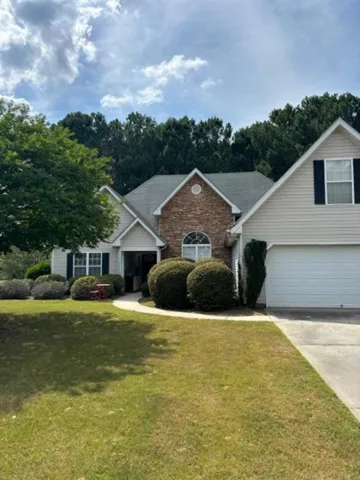 Exterior featuring a brick facade accent, horizontal siding, an arched window, and an attached garage with a white door
