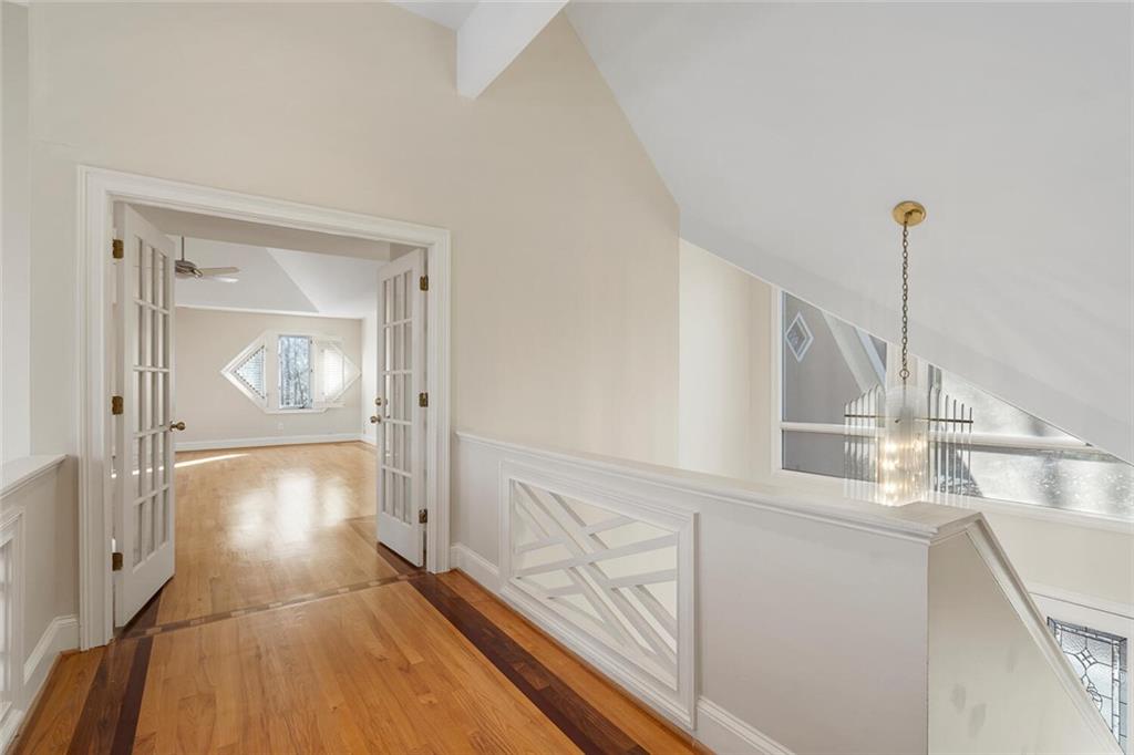 Hallway featuring a notable chandelier, lofted ceiling, light hardwood / wood-style flooring, and french doors
