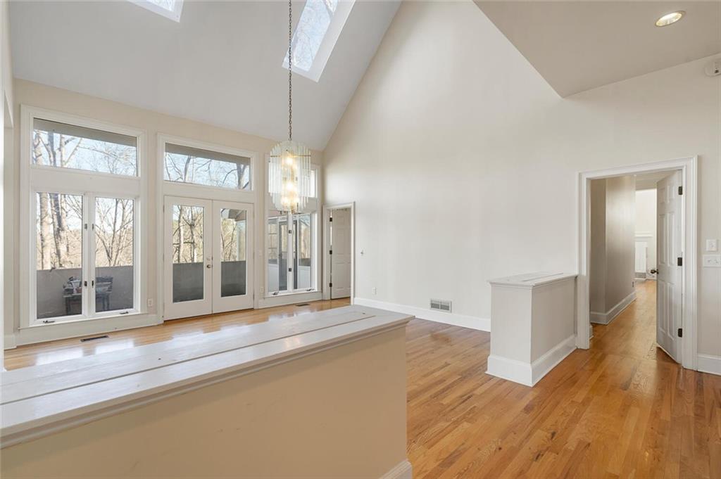 Hall with light hardwood / wood-style flooring, plenty of natural light, and high vaulted ceiling
