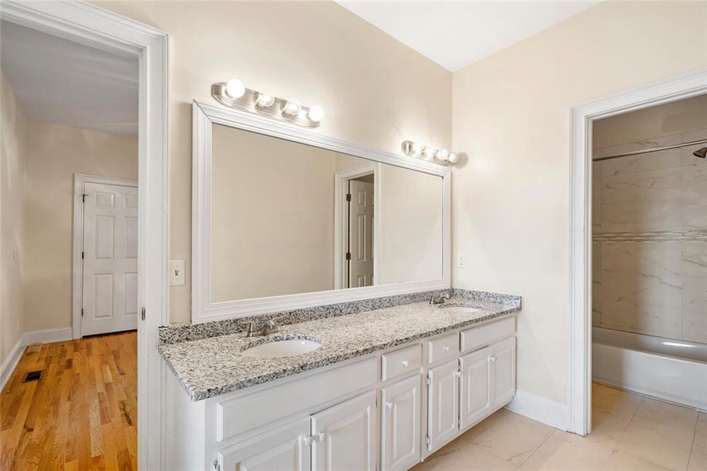 Bathroom featuring dual sinks, oversized vanity, tub / shower combination, and hardwood / wood-style flooring