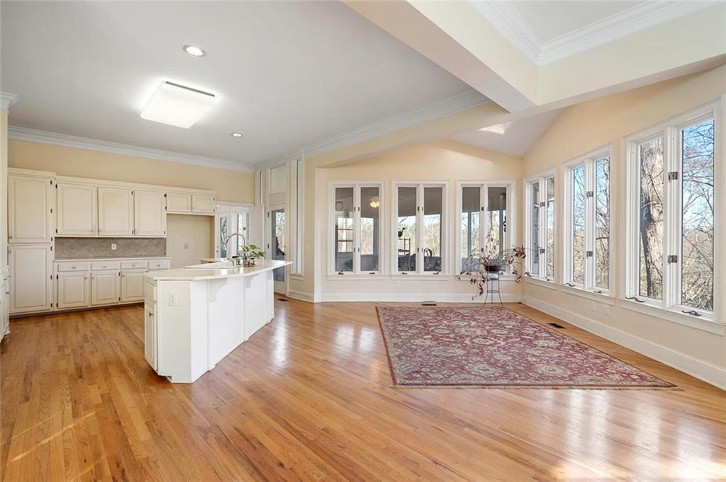 Kitchen featuring sink, a kitchen island with sink, light hardwood / wood-style floors, white cabinets, and backsplash