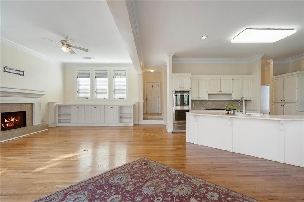 Kitchen with sink, light hardwood / wood-style floors, ceiling fan, a fireplace, and ornamental molding
