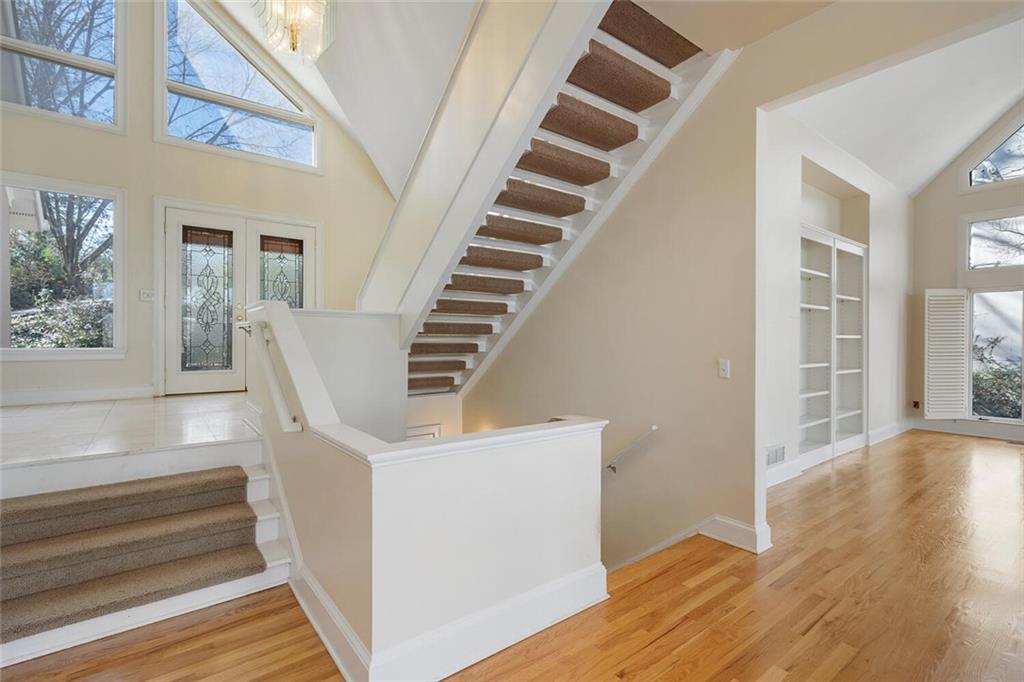 Stairway featuring an inviting chandelier, built in shelves, a high ceiling, and plenty of natural light