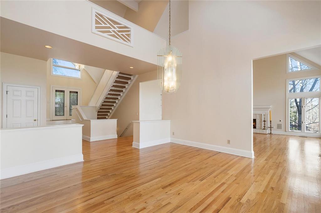 Empty room with a high ceiling, light hardwood / wood-style floors, and plenty of natural light
