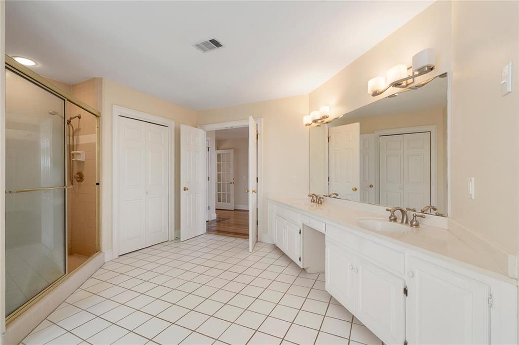 Bathroom featuring tile floors, dual bowl vanity, and a shower with shower door
