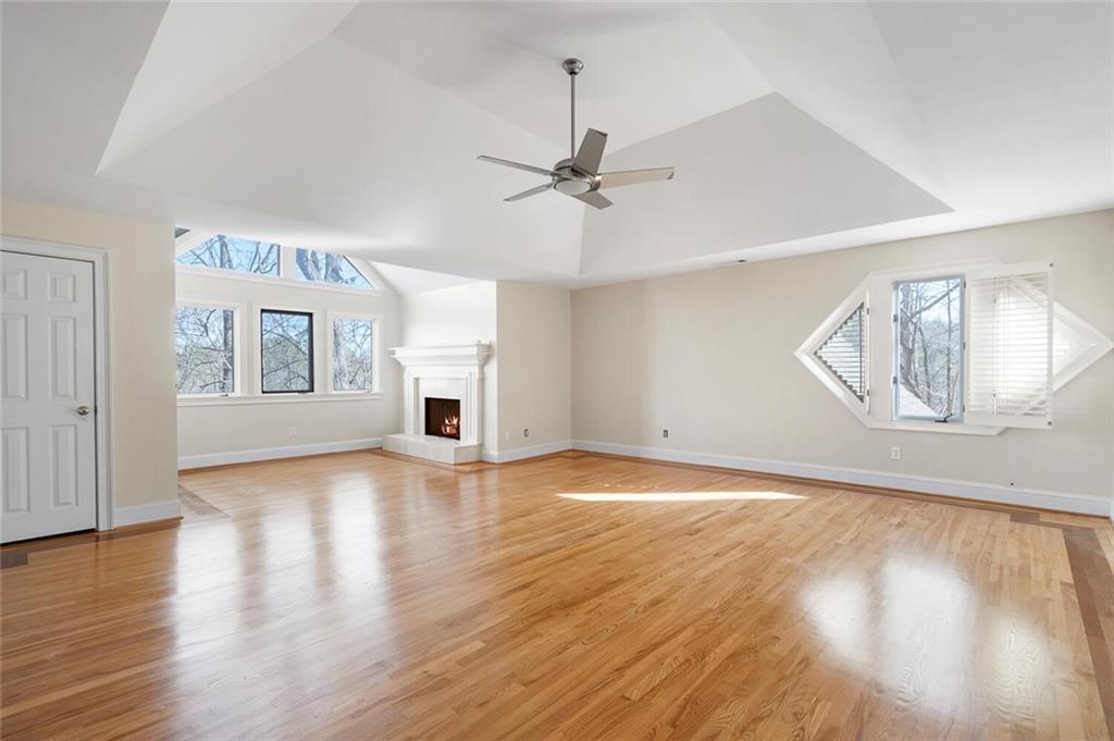 Unfurnished living room featuring ceiling fan, a raised ceiling, and light hardwood / wood-style floors