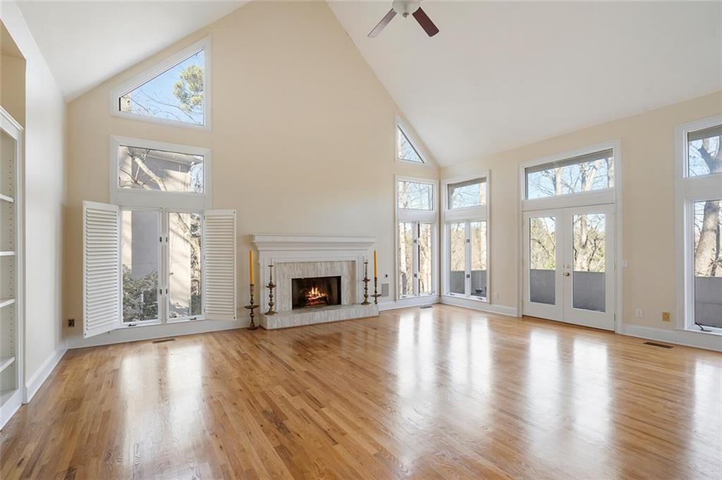 Unfurnished living room with light wood-type flooring, ceiling fan, high vaulted ceiling, and french doors