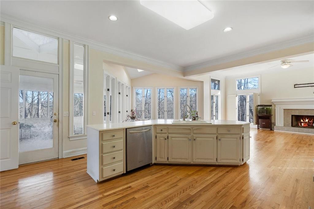 Kitchen featuring sink, light hardwood / wood-style flooring, a tile fireplace, ceiling fan, and dishwasher
