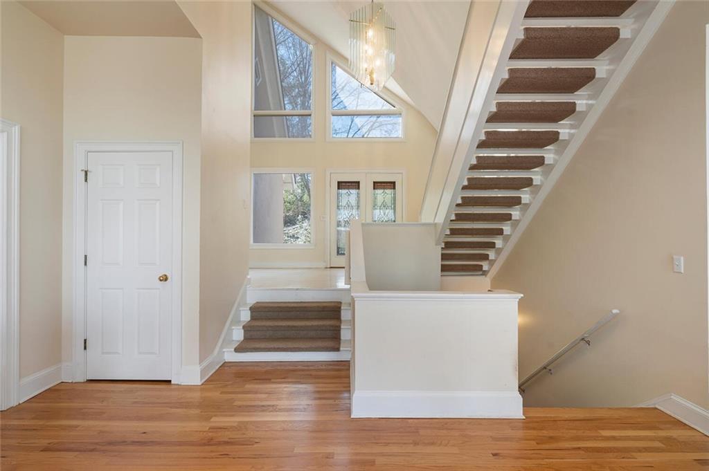 Staircase with an inviting chandelier, a towering ceiling, and light wood-type flooring