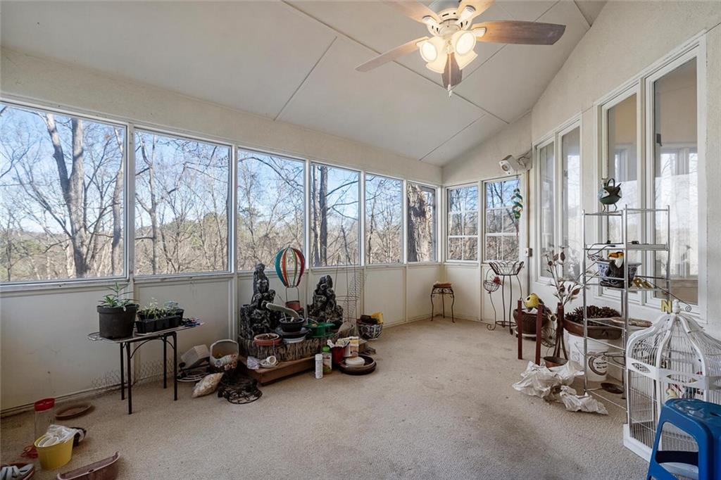 Sunroom / solarium with ceiling fan, a healthy amount of sunlight, and vaulted ceiling