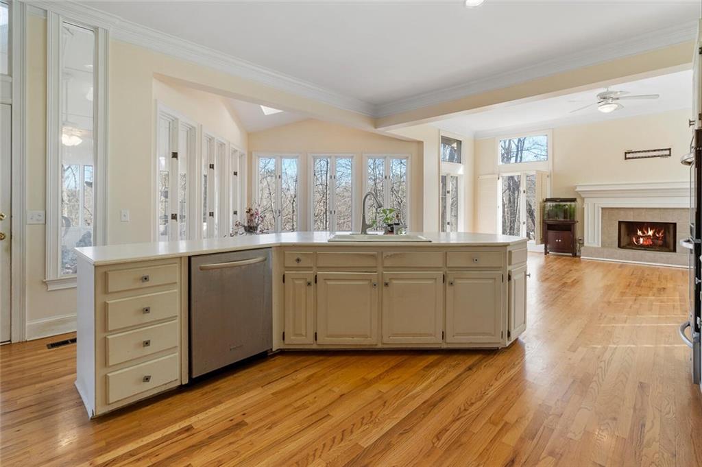 Kitchen with dishwasher, sink, light hardwood / wood-style floors, ceiling fan, and cream cabinets