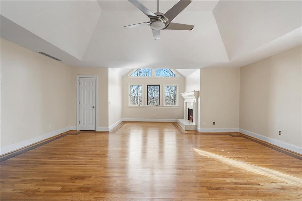 Unfurnished living room featuring ceiling fan, light wood-type flooring, and vaulted ceiling