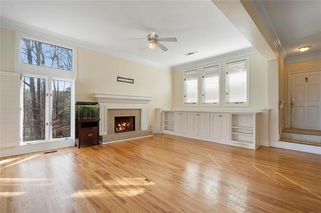 Unfurnished living room with a fireplace, ceiling fan, light hardwood / wood-style floors, and crown molding
