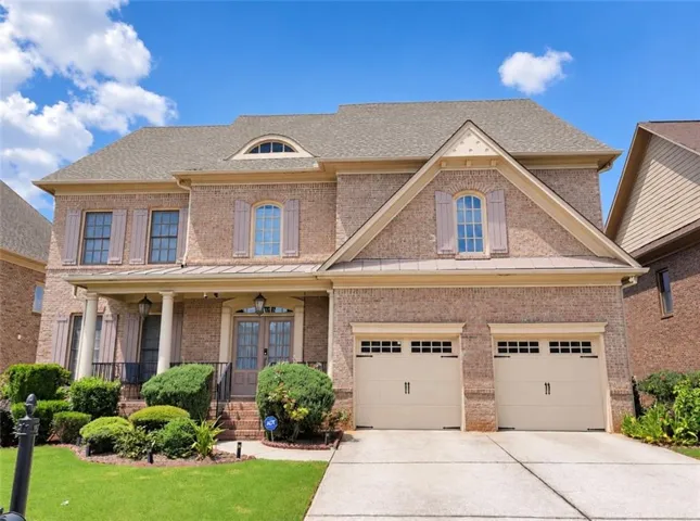 Brick exterior with a covered porch, column accents, and a two-car garage