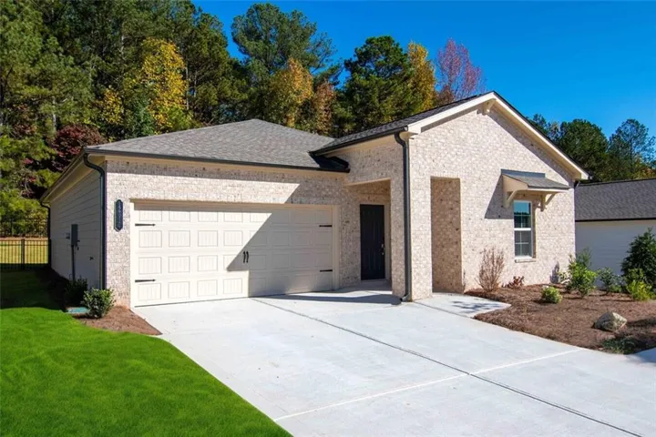 View of front of property featuring a garage, concrete driveway, and brick siding