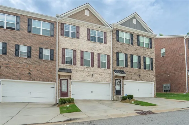 Brick and siding exterior featuring white garage doors, a covered front entry, and multiple windows with contrasting shutters