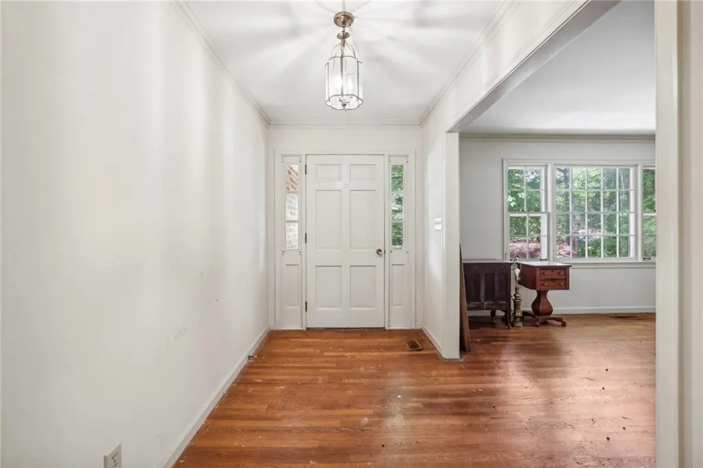 Foyer entrance featuring crown molding and wood-type flooring
