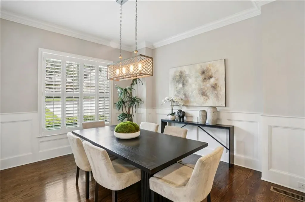 Formal Dining with wainscoting, a decorative wall, ornamental molding, and dark wood-style flooring