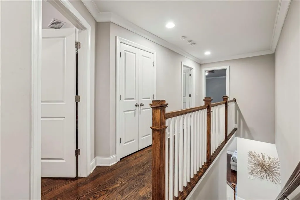 Corridor featuring an upstairs landing, dark wood-type flooring, crown molding, and recessed lighting