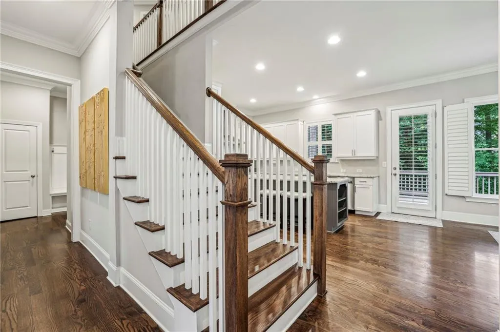 Staircase with ornamental molding, wood finished floors, and recessed lighting