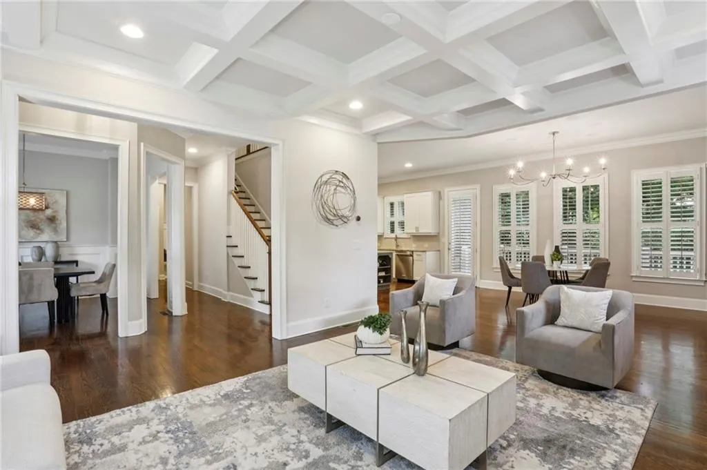 Living area featuring ornamental molding, a chandelier, hardwood floors, coffered ceiling, and beamed ceiling