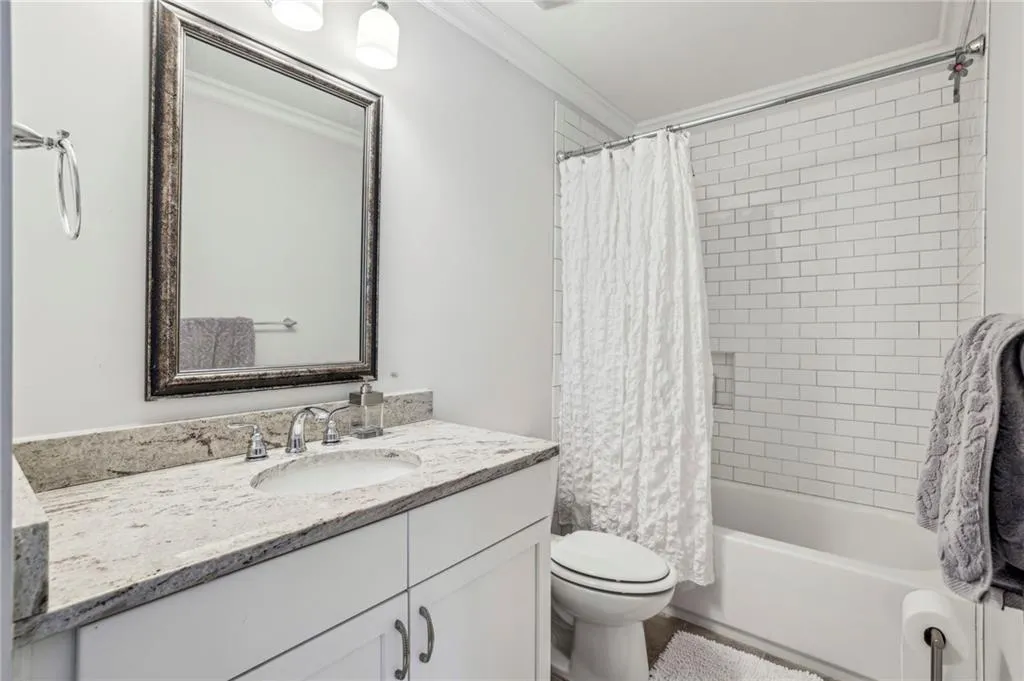 Full bath with shower / tub combo with curtain, vanity, and ornamental molding