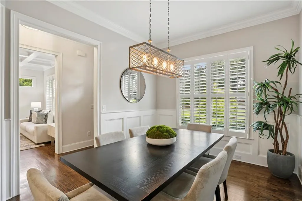 Formal dining room  featuring ornamental molding, dark wood-style floors, plenty of natural light, a decorative wall, and wainscoting